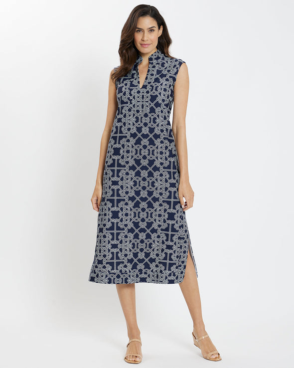 Brunette woman wearing geometric print navy and white rope print midi dress with tan wedge sandals