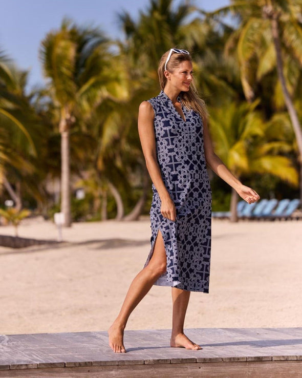 Woman on beach walkway in front of palm trees wearing navy & white geometric print midi dress and white sunglasses on top of her head