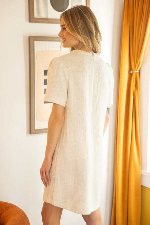 Back of blonde woman in white tweed dress 