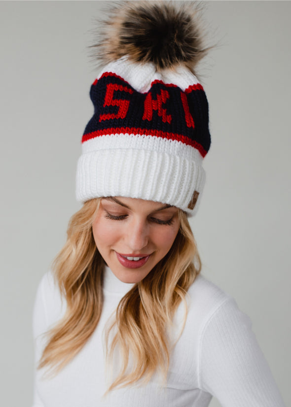 Model with a white pom pom hat that says ski