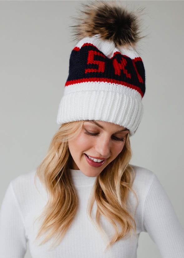 Model in the white, blue, and red pom pom hat that says Ski