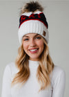 Smiling model in a white, navy and red pom pom hat