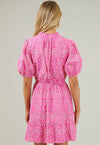 Blonde woman facing away from the camera wearing pink puff sleeve lace mini dress