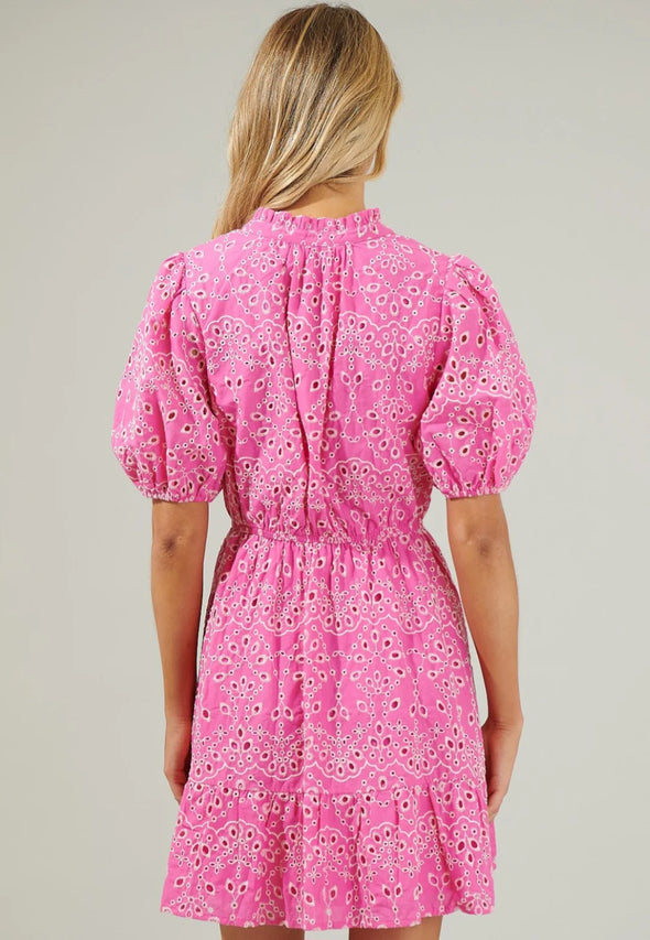 Blonde woman facing away from the camera wearing pink puff sleeve lace mini dress