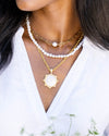 Black model in white v-neck shirt wearing 3 layered necklaces with gold and pearl